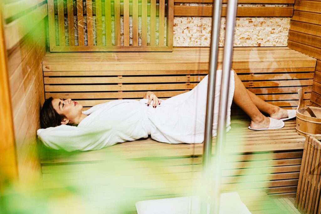 Woman relaxing in a wooden sauna.