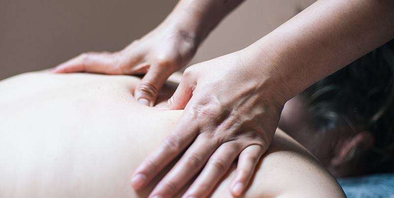 Hands performing a back massage.