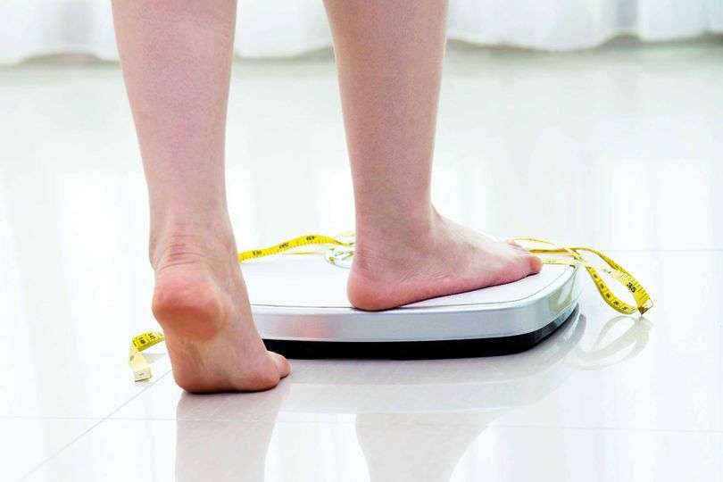 Person weighing themselves on scale.