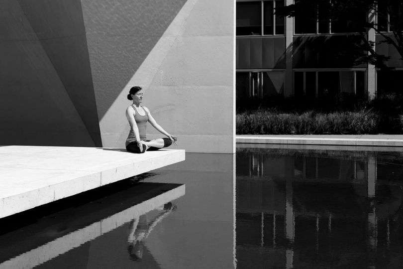 Woman meditating by tranquil water.