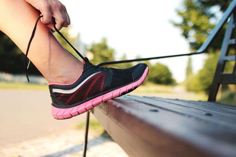 Woman tying pink and black running shoe.
