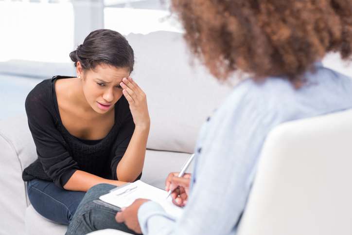 Woman distressed, therapist taking notes.