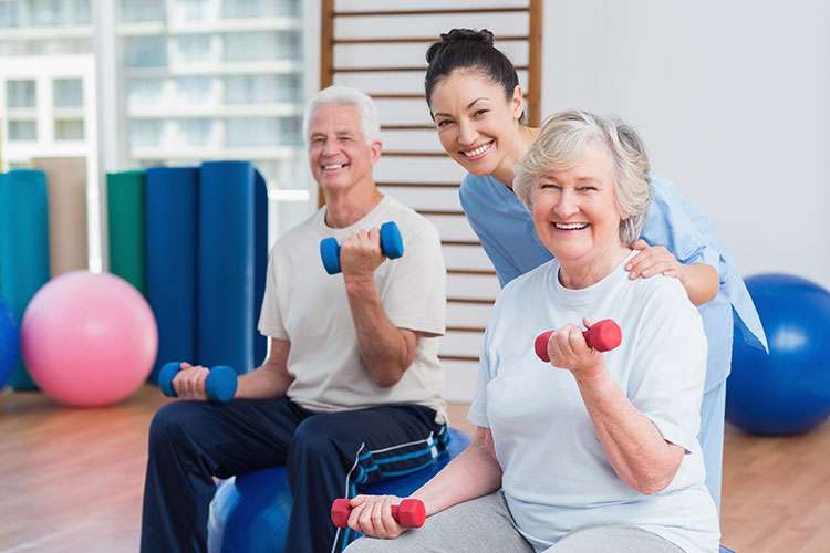 Seniors exercising with weights and a trainer.